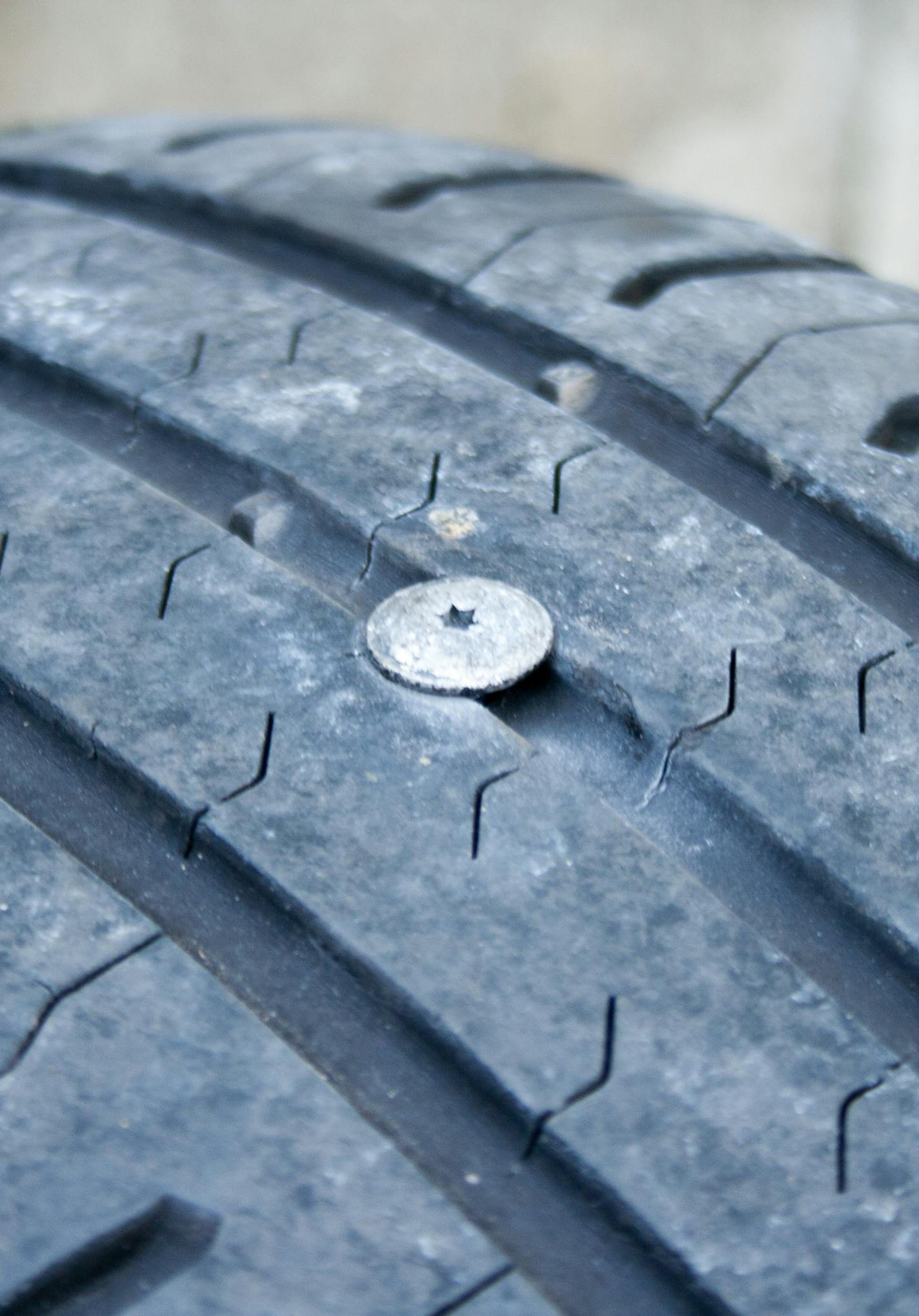 A punctured tire. A nail stuck in the car tire.