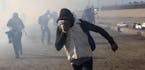 FILE - In this Nov. 25, 2018 file photo, a migrant runs from tear gas launched by U.S. agents, amid members of the press covering the Mexico-U.S. bord