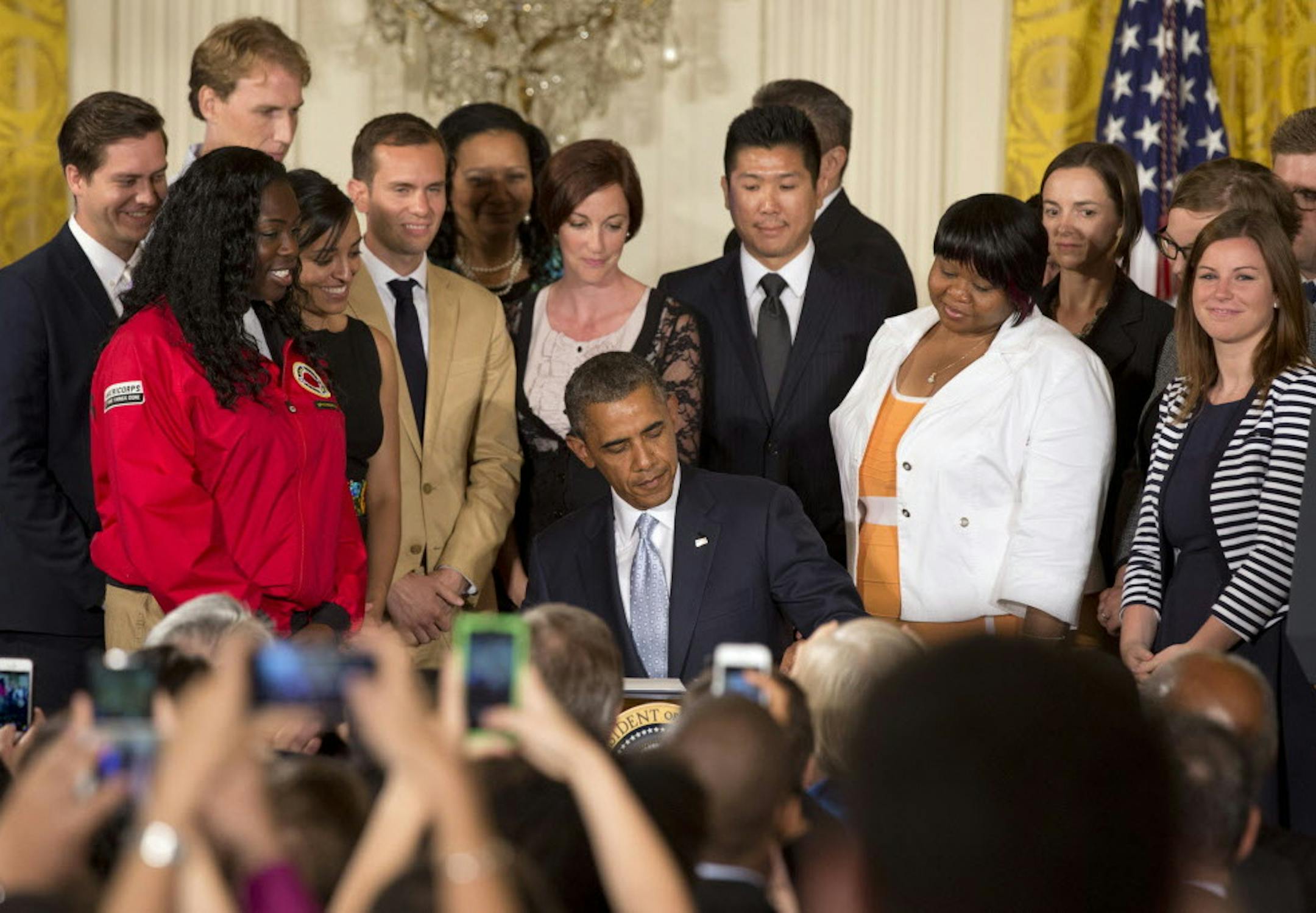Surrounded by college students, President Barack Obama signs a Presidential Memorandum on reducing the burden of student loan debt, Monday, June 9, 2014, in the East Room of the White House in Washington. The president said the rising costs of college have left America's middle class feeling trapped. He says no hard-working youngster in America should be priced out of a higher education. Obama signed a presidential memorandum he says could help an additional 5 million borrowers. (AP Photo/Jacque