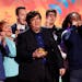 FILE - Dan Schneider, center, accepts an award in Los Angeles. Schneider sued the makers of “Quiet on Set: The Dark Side of Kids TV” on Wednesday,
