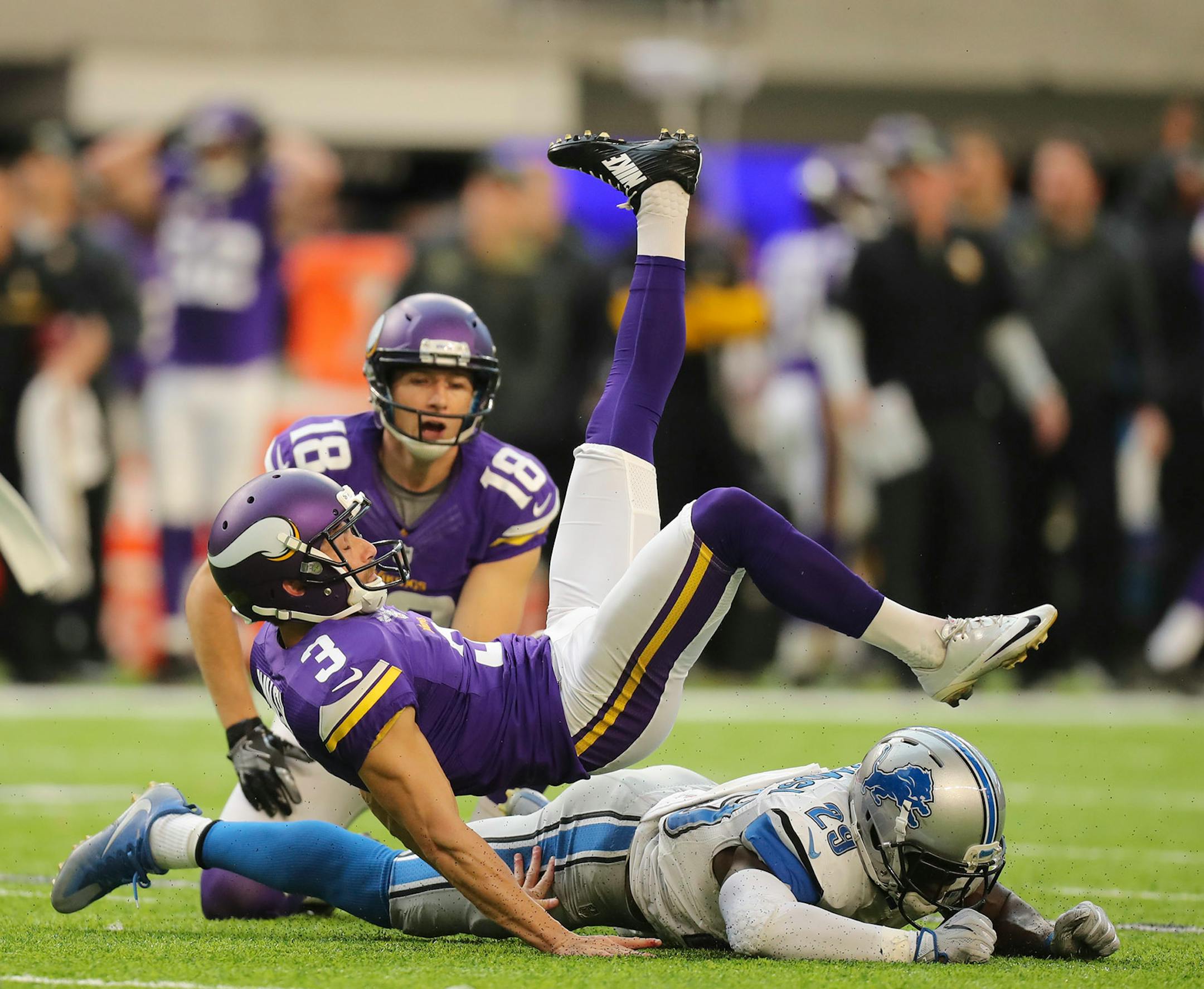 Vikings kicker Blair Walsh (3) was upended by Detroit Lions cornerback Johnson Bademosi (29) after he kicked the extra point following the Vikings fourth quarter touchdown.