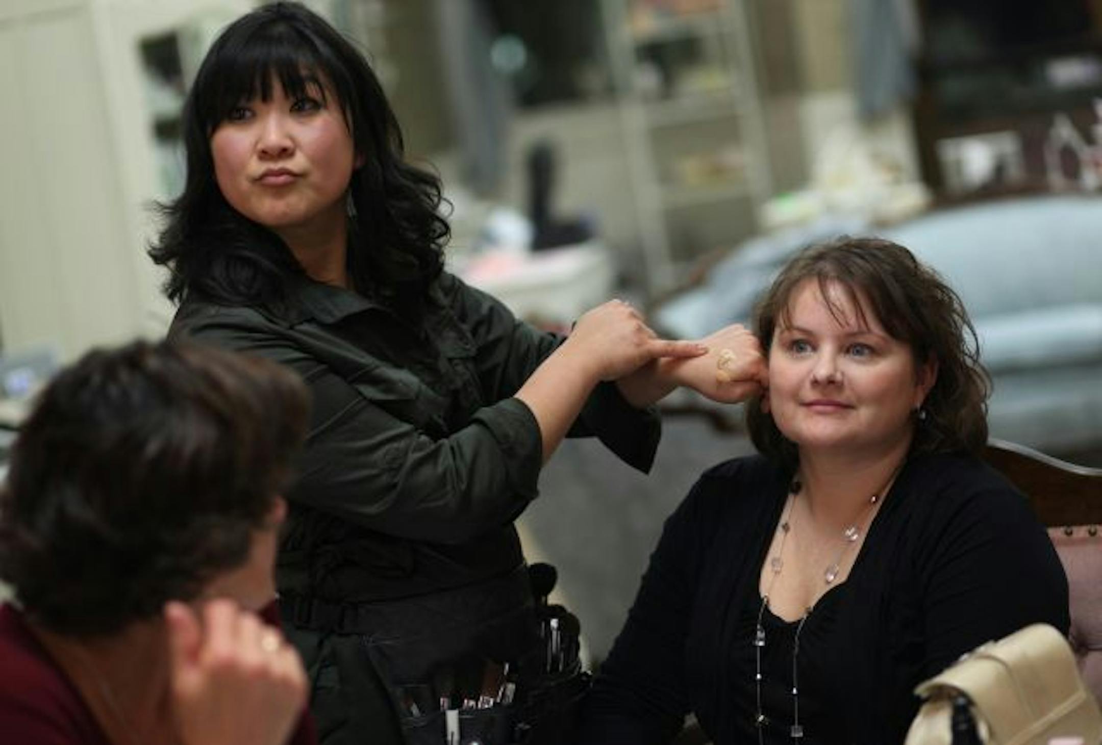 Smart and Chic owner Julie Swenson, left, compared different shades of foundation on her hand next to Jen Kos' face during a group makeup lesson.
