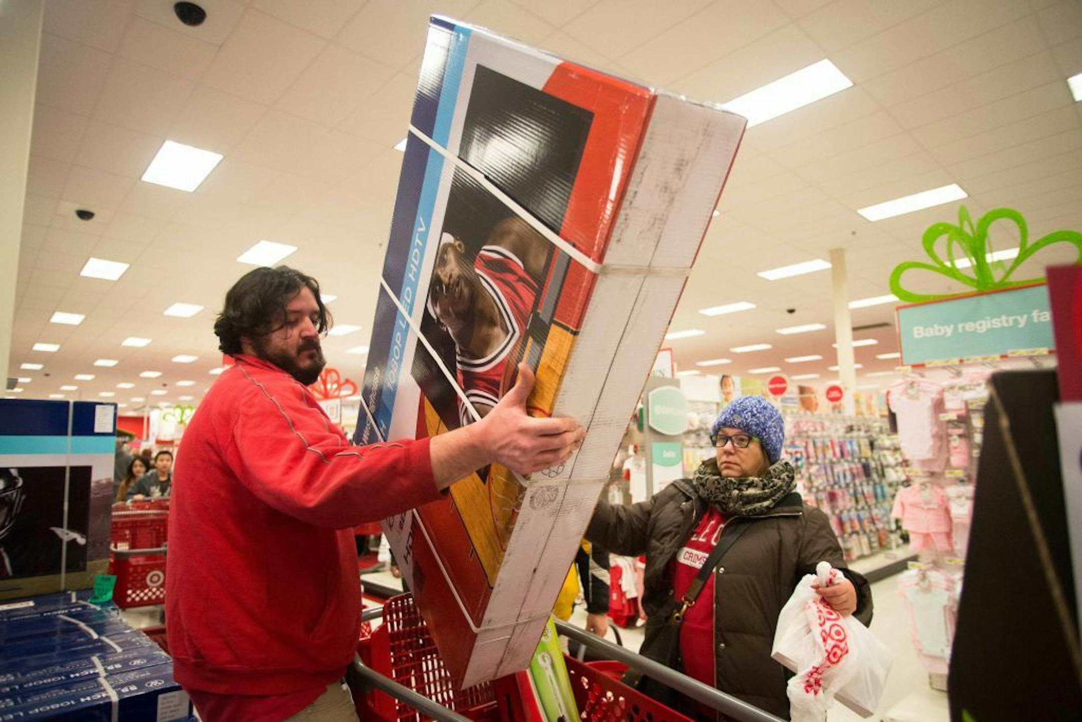 Super Target employee Jeremy Streit helps lift a big screen television into the cart of Tonii Simmons during Thanksgiving night shopping.