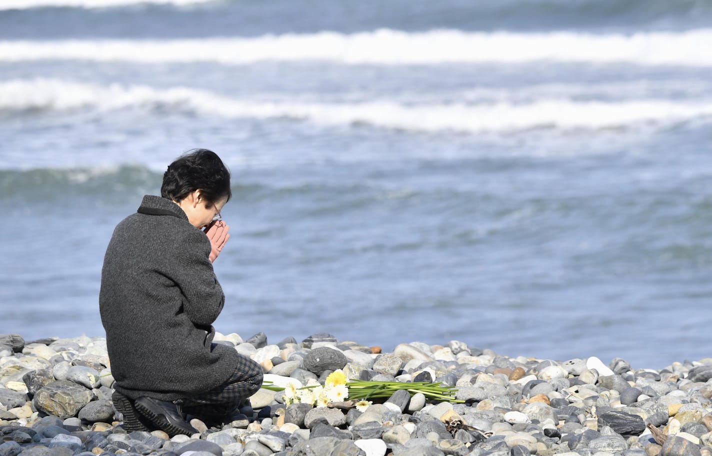 A woman prayed toward the sea for the victims of the 2011 tsunami in Kesennuma, Japan.