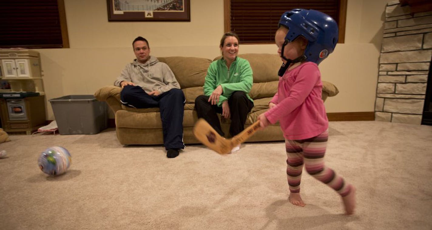 Hitting a Disney princess ball with a plastic stick in the basement is hockey for 2-year-old Anna, watched by parents Johnny Pohl and Krissy (Wendell) Pohl.