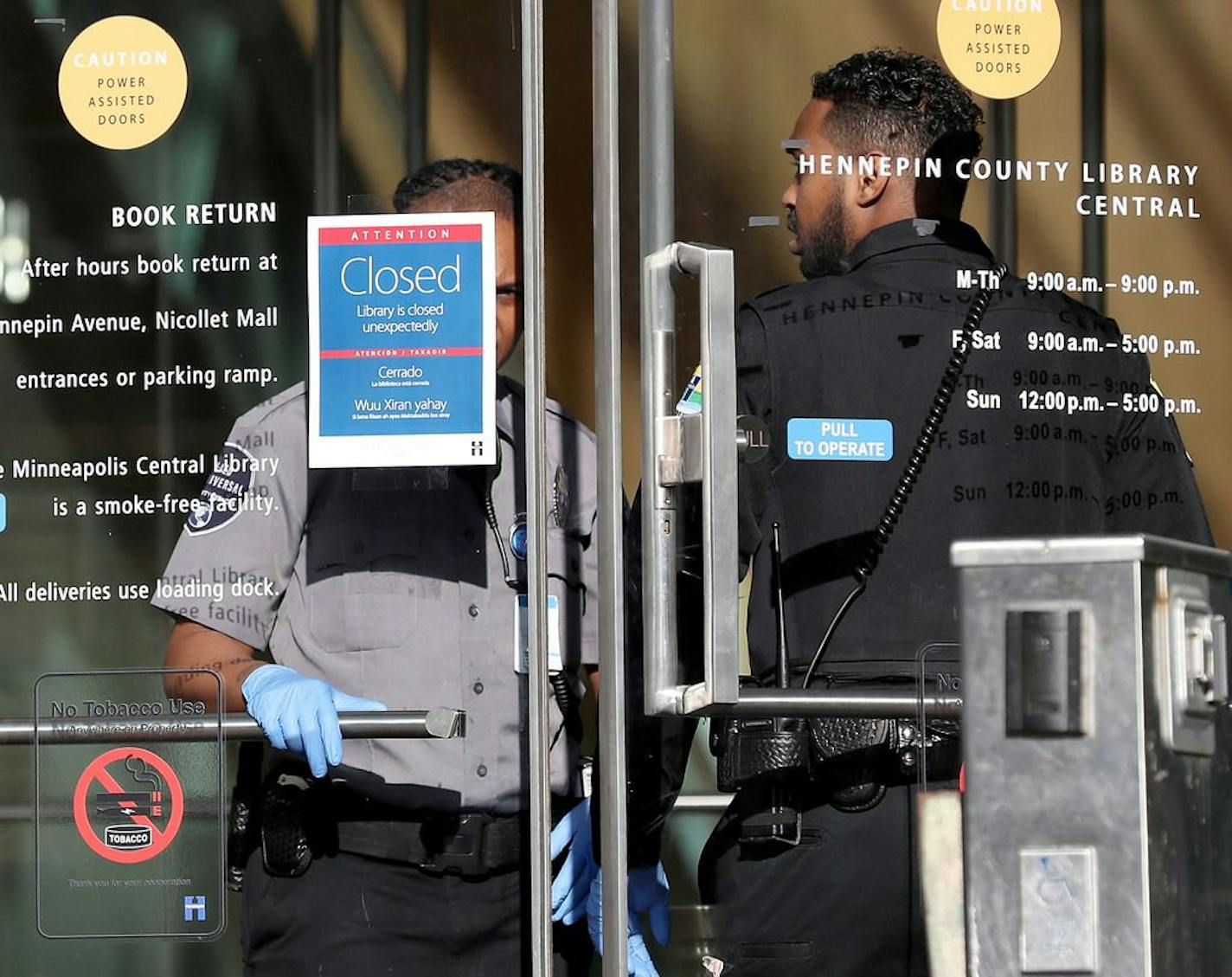 Security guards stand at the door to the downtown Minneapolis Public Library, turning away patrons after the library closed amid the coronavirus spread Tuesday, March 17, 2020, in Minneapolis.