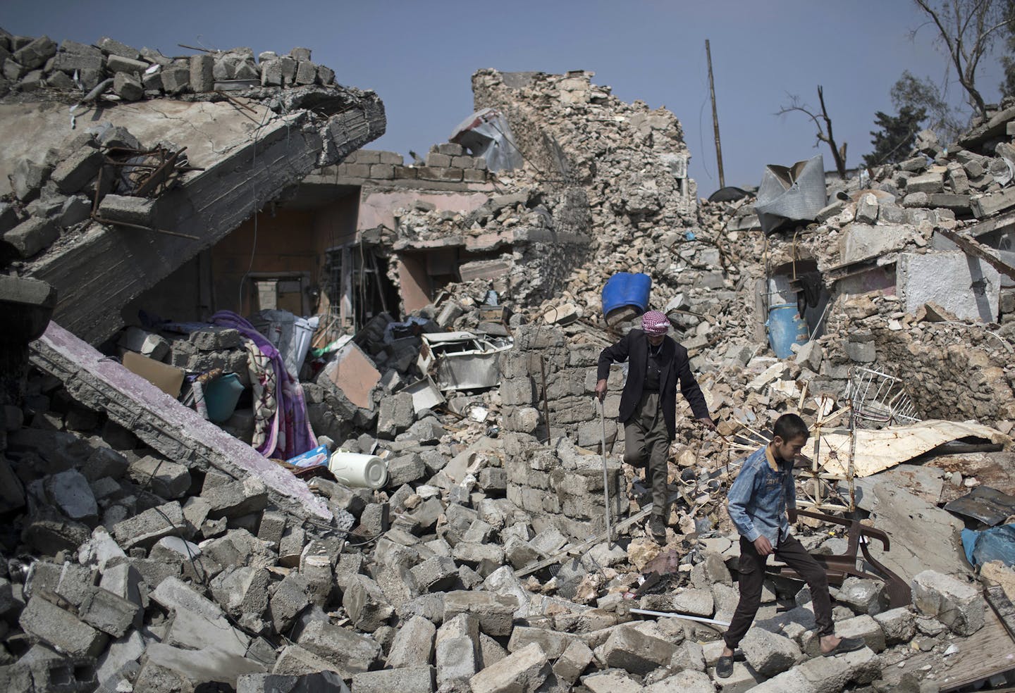 Residents walk amid the rubble of buildings they say were destroyed by airstrikes, in a neighborhood recently retaken by Iraqi security forces from Islamic State militants, on the western side of Mosul, Iraq, Sunday, April 2, 2017. (AP Photo/Felipe Dana) ORG XMIT: MIN2017040714171467