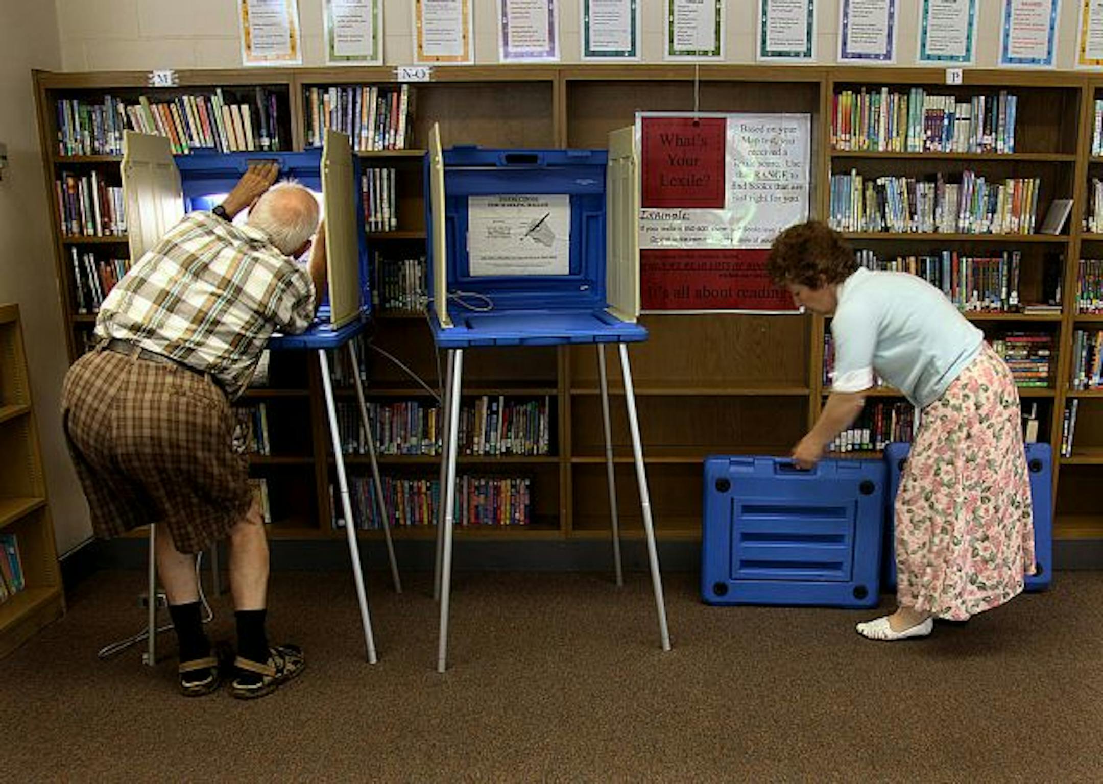 Adrian Swanson, left, and Maria Loomis set up voting booths Monday at Northeast Middle School in Minneapolis.