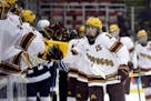Minnesota forward Rem Pitlick is greeted by teammates after scoring during the first period of an NCAA college hockey semifinal match against Penn Sta