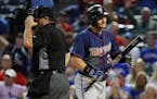 Home plate umpire Tony Randazzo, left, stands by the plate as Minnesota Twins' Robbie Grossman walks back to the dugout after striking out leaving the