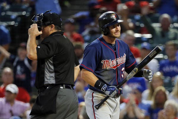 Home plate umpire Tony Randazzo, left, stands by the plate as Minnesota Twins' Robbie Grossman walks back to the dugout after striking out leaving the