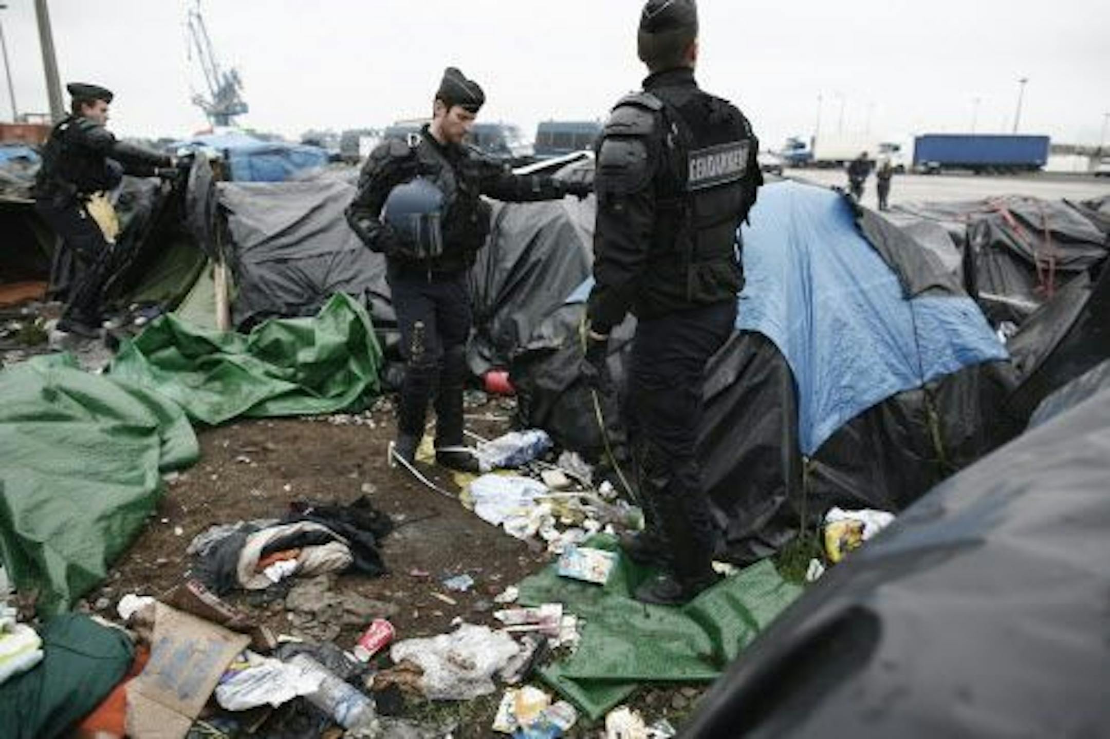 Police officers take positions in a makeshift camp housing hundreds of illegal migrants after French authorities started to clear out camps in the English Channel port city of Calais, northern France, Wednesday, May 28, 2014.