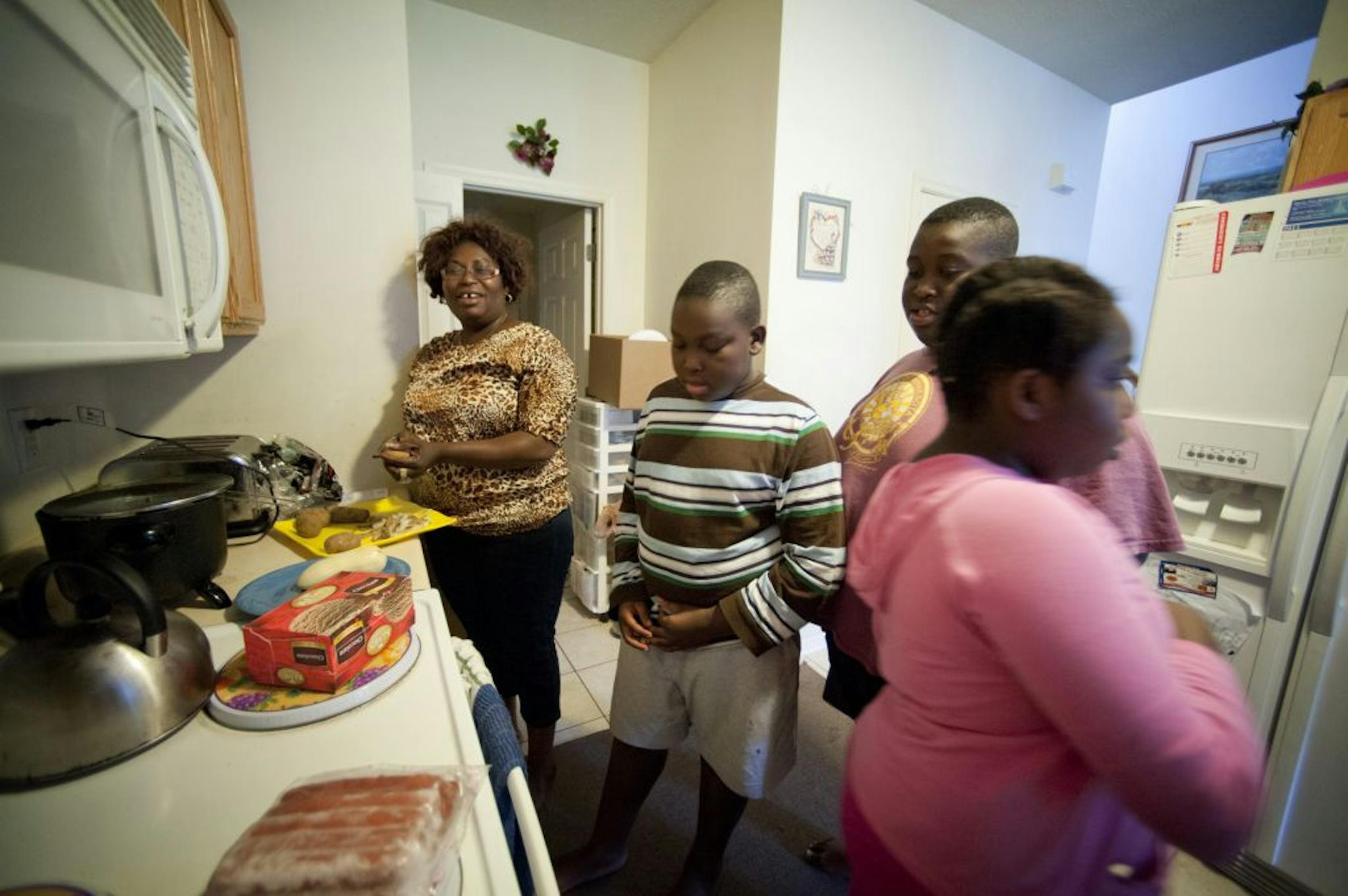 Gloria Agbator, a single mom with pneumonia, fears her uninsured children will get sick, too. "This program is going to be a really good blessing to my family," she said. Here she started dinner Thursday for, from left, Joseph, 9, Daniel, 13, and Elizabeth, 9, at their Apple Valley home.