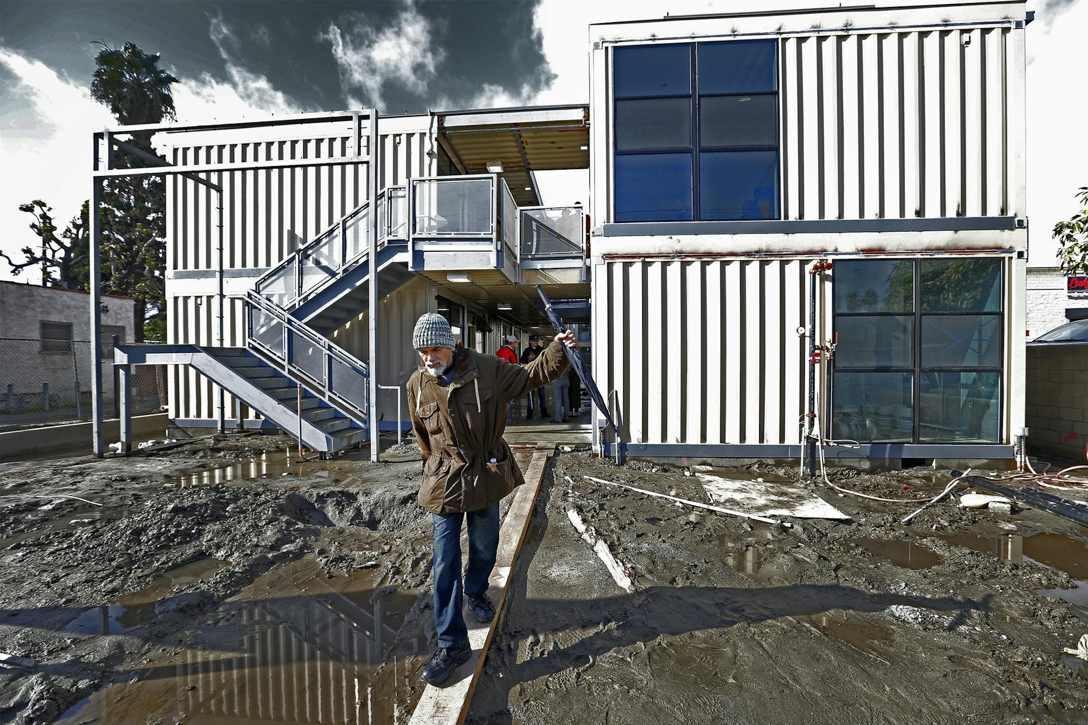 Previously homeless Army veteran Kenneth Salazar, who was homeless on and off for ten years-most recently at the courtyard downtown Santa Ana bus terminal, walks across a board while checking on the construction progress at Potter's Lane in Midway City. Potter's Lane is billed as the nation's first multi-family housing development built with recycled shipping containers to provide permanent supportive housing for homeless veterans. Shipping containers that have been converted into modular housin