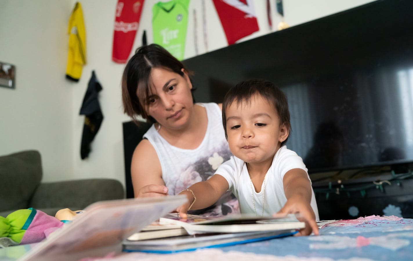 Vanessa Del Campo read with her daughter Regina in their Minneapolis apartment. She is one of the tenants who received a payout in a class-action settlement against landlord Stephen Frenz.