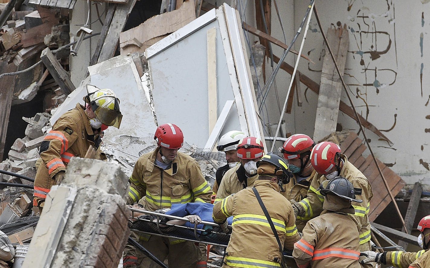 Emergency crews rescue a woman from a building collapse Friday Dec. 2, 2016 in downtown Sioux Falls. Two people were trapped inside the building, which was undergoing construction at the time of the collapse. A fire official says rescue workers are concerned about debris shifting as they try to free the people. (Joe Ahlquist/Argus Leader via AP)