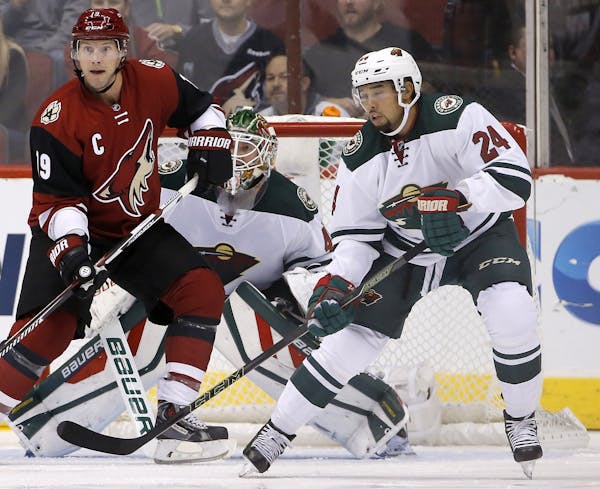 Arizona Coyotes' Shane Doan (19), Minnesota Wild's Matt Dumba (24) and Wild goalie Devan Dubnyk, middle, watch as the puck is hit at them during the f