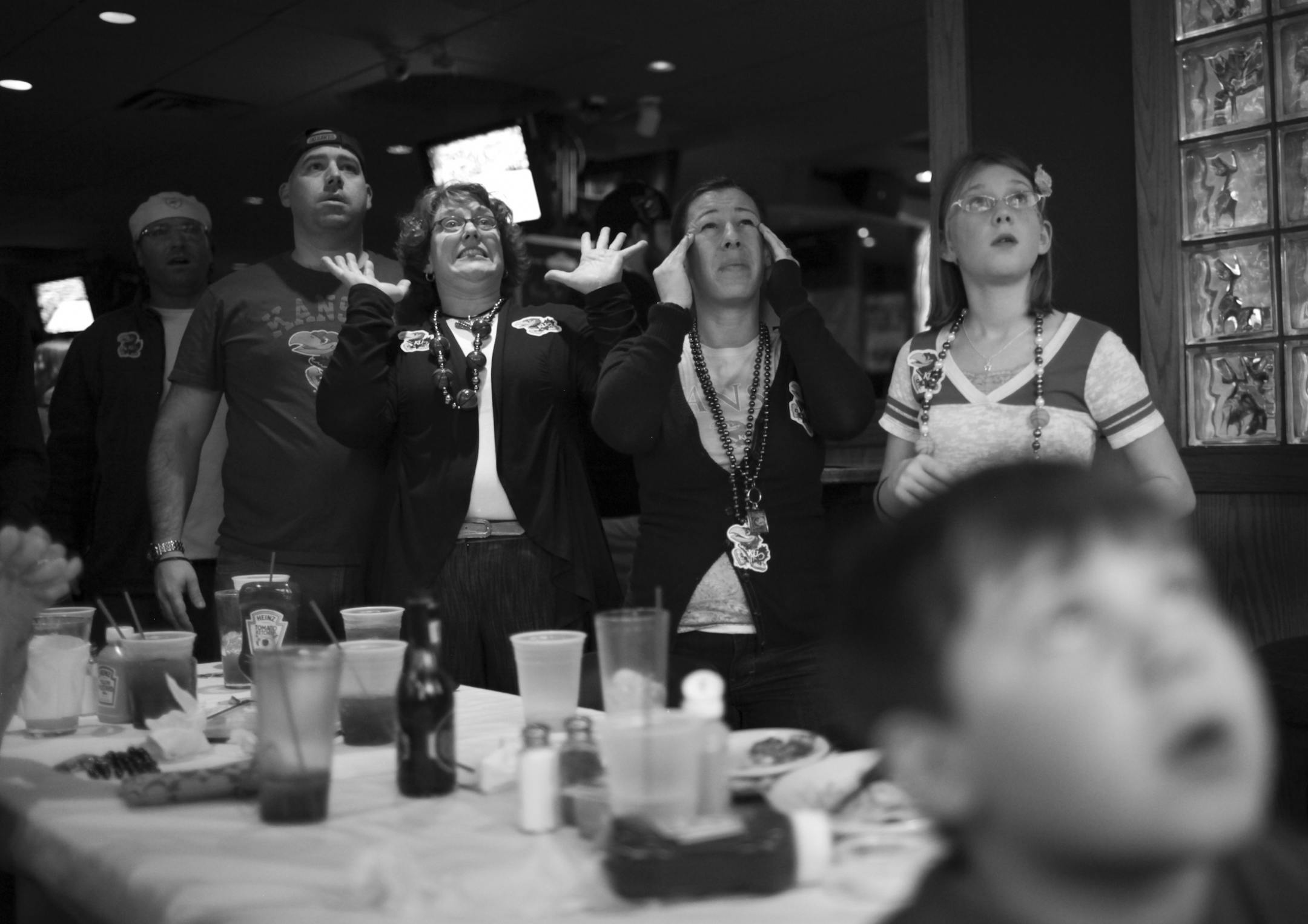 Jake Spano grew up watching University of Kansas basketball games after his father started teaching at the university in 1975. With his mother and sister visiting for the weekend from Lawrence, his extended family gathered at the Tiffany Sports Lounge in St. Paul to watch the Jayhawks play Boston University in their NCAA basketball tournament game Friday night. Jake, second from left, watched a tense moment with his wife, Cate McDonald, his sister, Kate Carnahan, and his daughter, Mia, from left