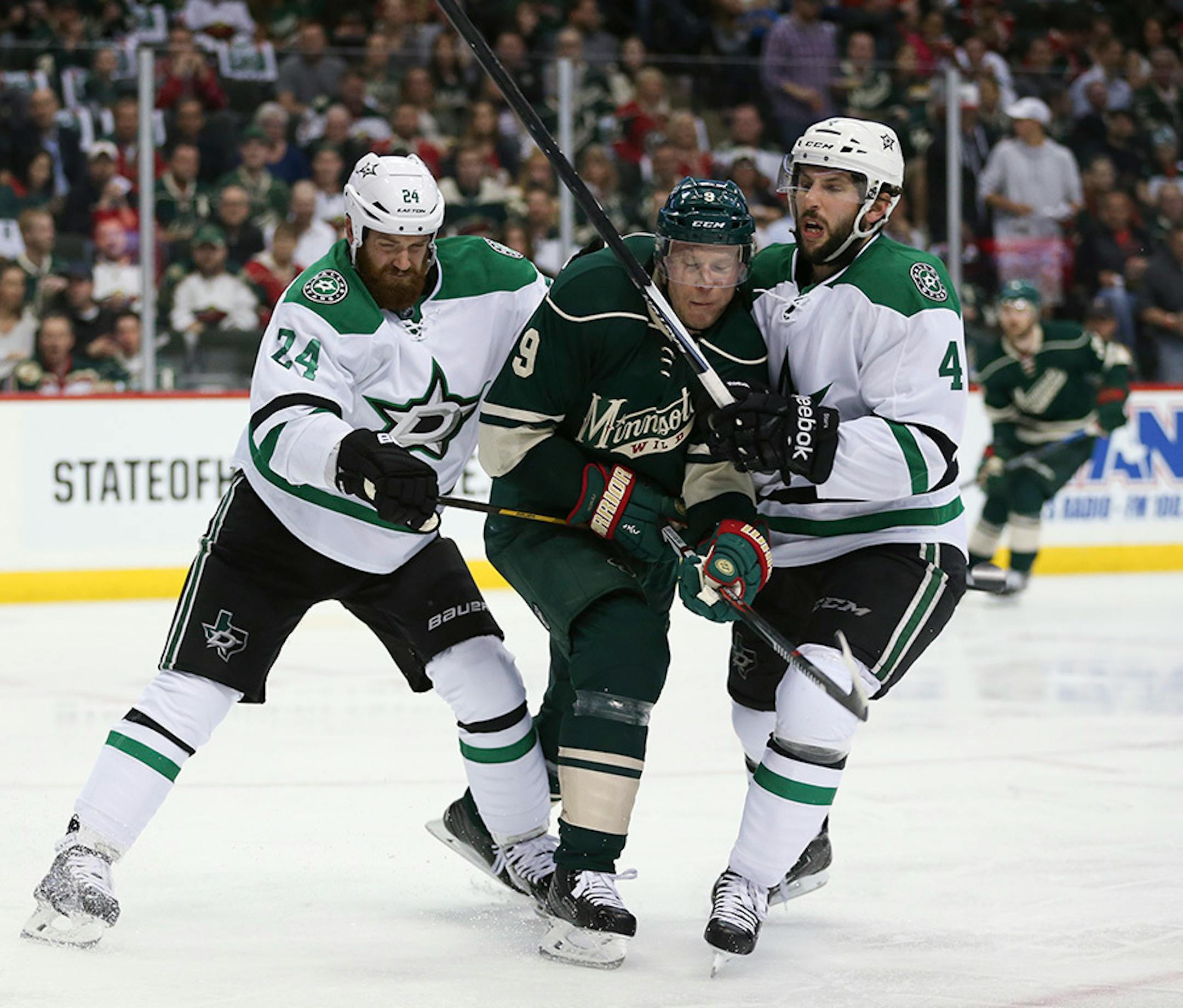 Wild center Mikko Koivu (9) was roughed up in the second period as he was sandwiched between Dallas Stars defensemen Jordie Benn (24) and Jason Demers (4).