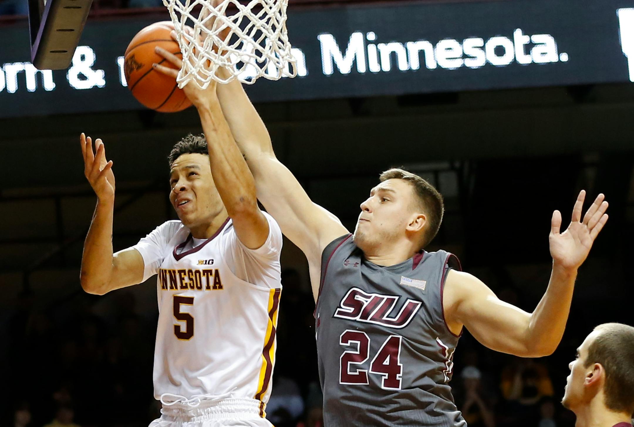 Minnesota's Amir Coffey, left, lays up a shot as Southern Illinois' Rudy Stradnieks defends during the second half of an NCAA college basketball game Friday, Nov. 25, 2016, in Minneapolis. Coffey made the basket. (AP Photo/Jim Mone)