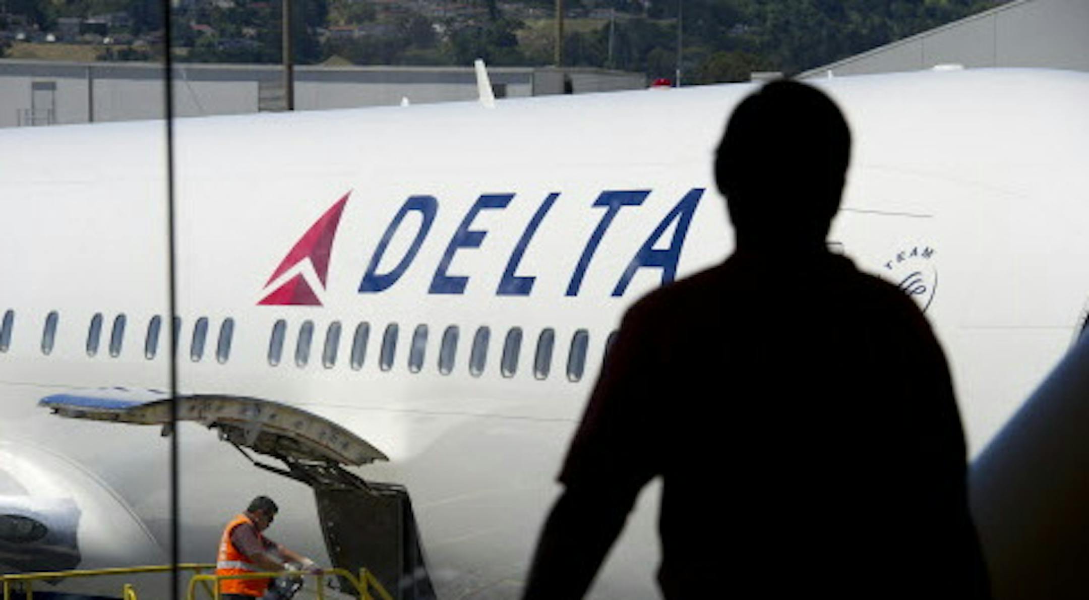 A passenger looks out towards a Delta Air Lines Inc. plane at San Francisco International Airport in San Francisco, California, U.S., on Tuesday, July 26, 2011. Delta Air Lines Inc., the world's second-largest airline, reported a second-quarter profit that trailed analysts' estimates as rising fuel costs damped results. Photographer: David Paul Morris/Bloomberg ORG XMIT: 120065651