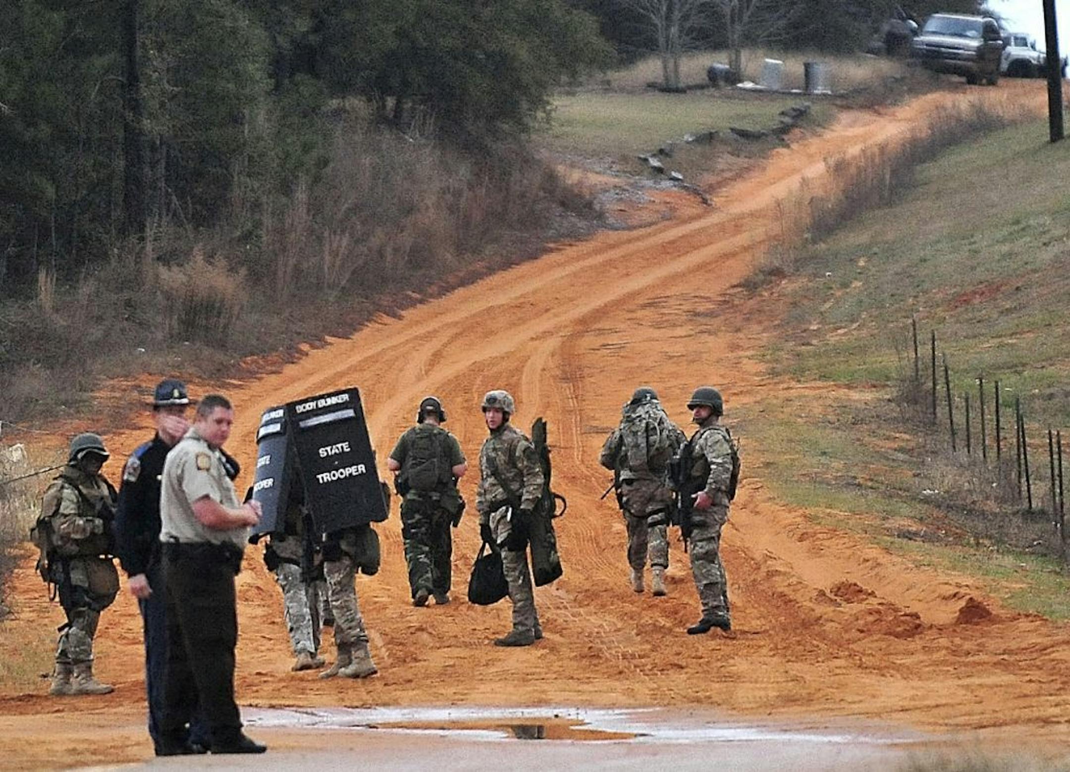 Law enforcement personnel work at check point Wednesday, Jan. 30, 2013, in Midland City, Ala., near the home where the Tuesday's school bus shooting suspect is barricaded in a bunker with a young child as hostage. Police, SWAT teams and negotiators were at a rural property where a man was believed to be holed up in a homemade bunker Wednesday after fatally shooting the driver of a school bus and fleeing with a 6-year-old child passenger, authorities said.