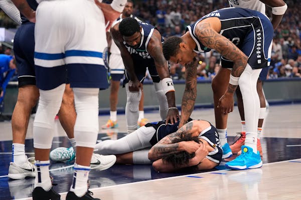 Mavericks center Dereck Lively is down on the court after falling and taking an inadvertent knee to the back of the head from Wolves center Karl-Antho
