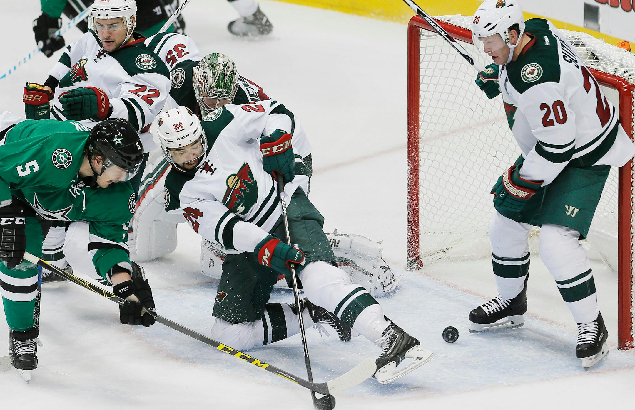 Stars defenseman Jamie Oleksiak (5) backhanded the puck past Wild defensemen Matt Dumba (24) and Ryan Suter (20) to score a goal during the second period Monday.