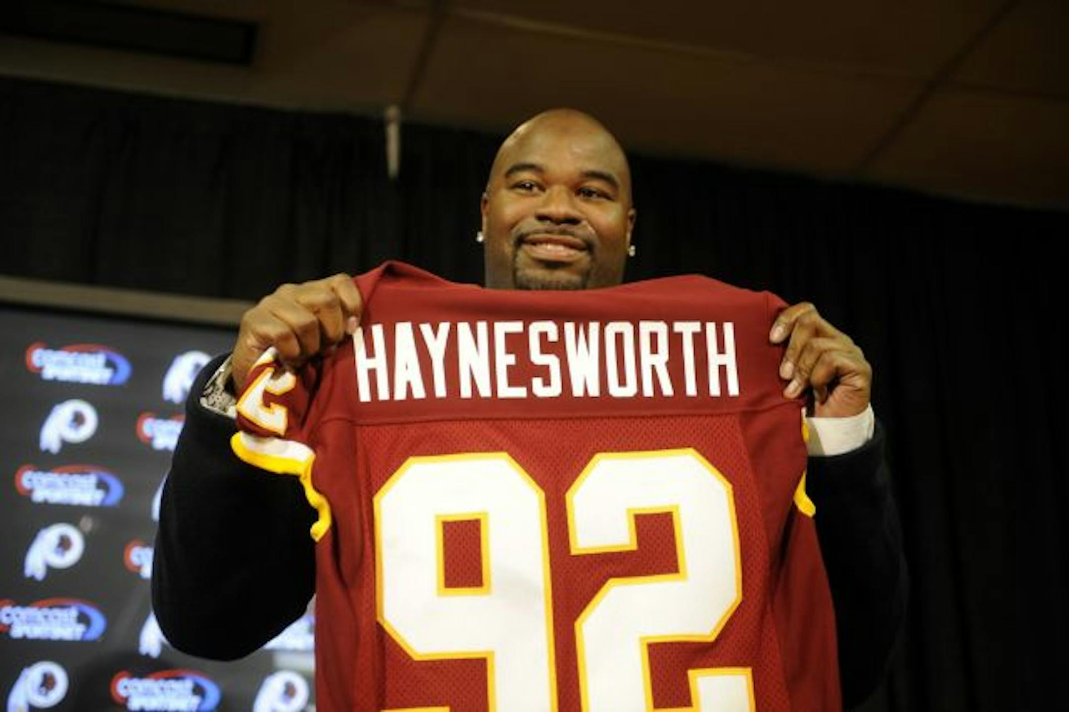 Albert Haynesworth posed with his new jersey at a press conference after signing a 7-year contract worth approximately $100 million with the Washington Redskins.