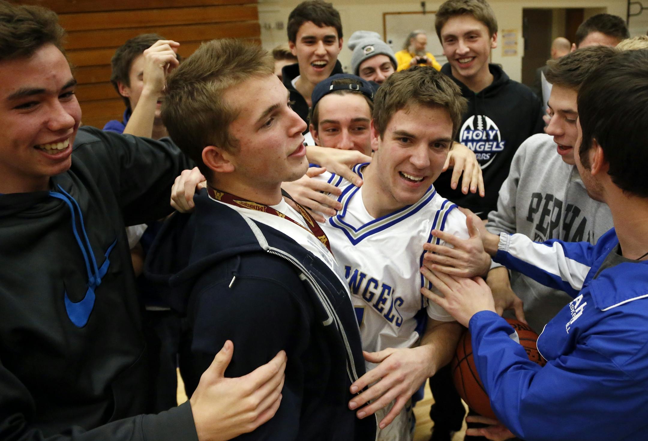 Holy Angels basketball team manager Nick Anderson was surrounded by students after playing in the final seconds of the game vs. Breck.