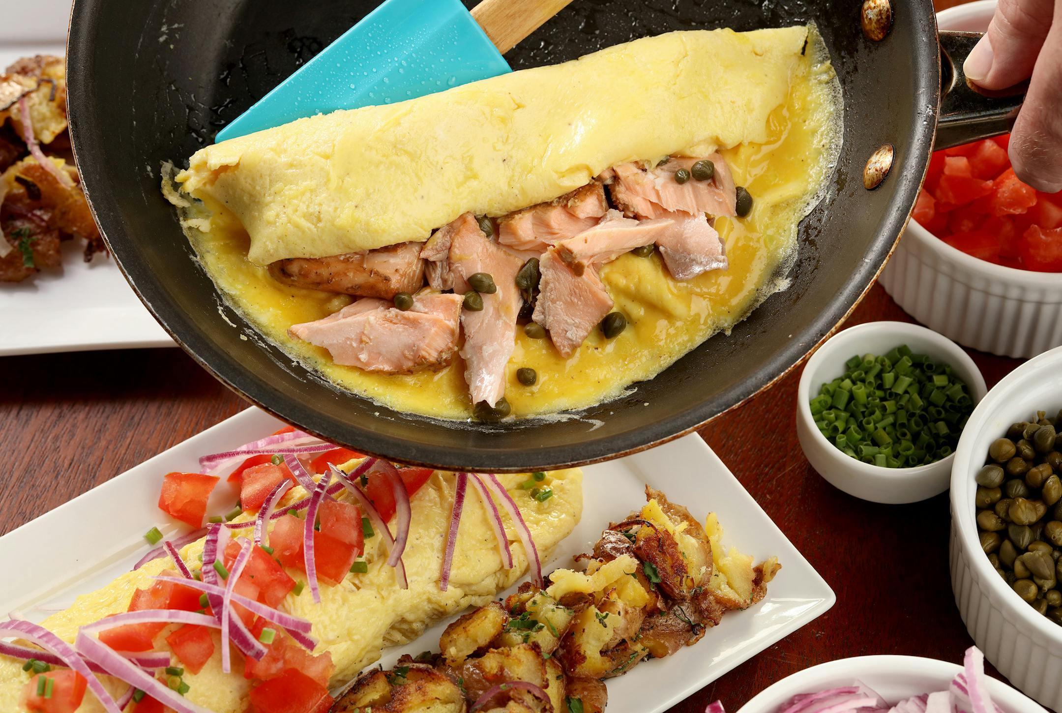 Smoked salmon grounds an omelet, with capers for a bright lift and a topping of chopped tomatoes, onions and chives.