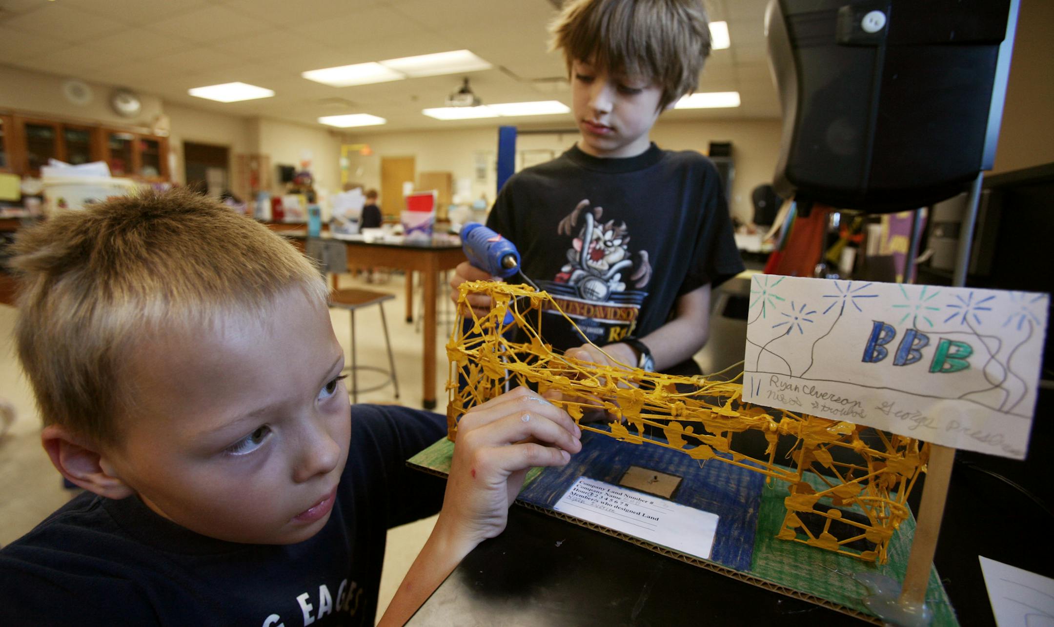 Ryan Iverson, 9, left, and teammate Nikos Stroubos, 10, put the finishing touches on a bridge Wednesday that they constructed at Summer Academy, a three-week summer program designed for students in the north metro who have been identified for Gifted/Talented programming in their school district.