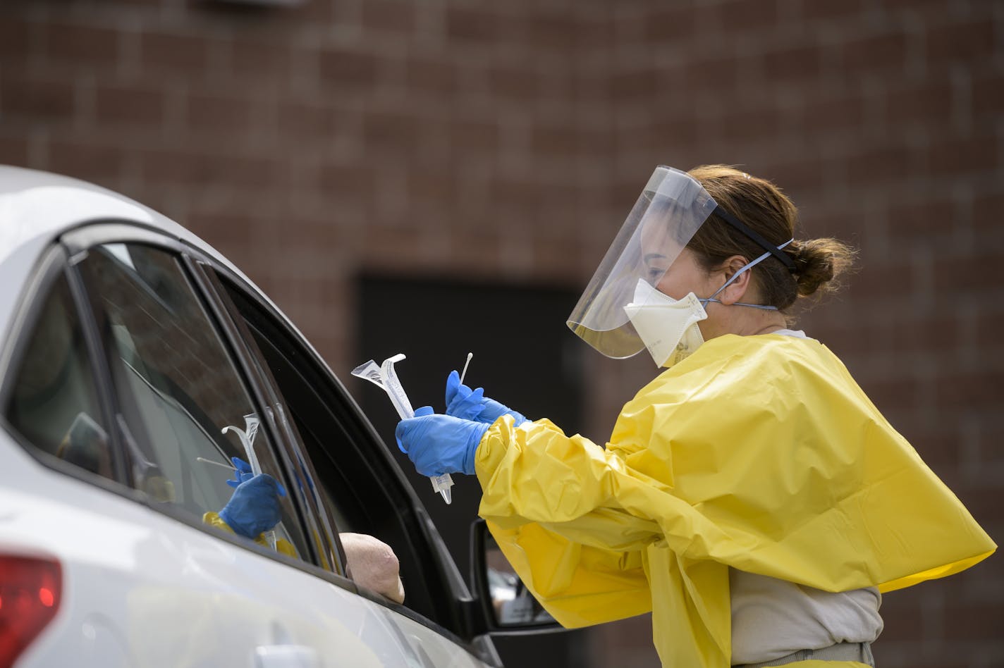 Elizabeth Santoro, a medic with the Minnesota Air National Guard 133rd Medical Group, administered a free COVID-19 test recently to a passenger at the drive-up testing site behind the Minneapolis Armory. Credit: Aaron Lavinsky, Star Tribune]