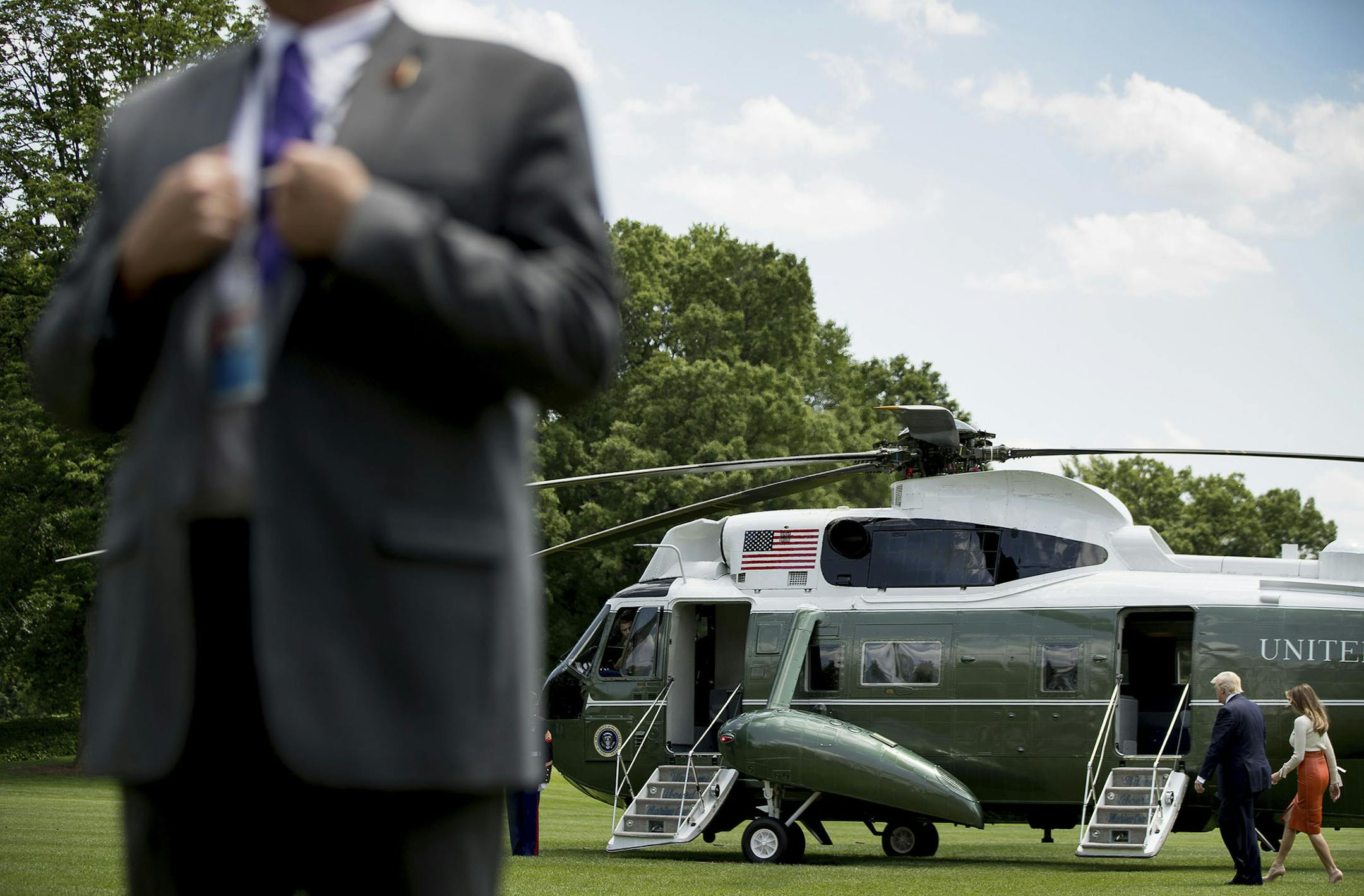 A member of the Secret Service stands guard as President Donald Trump and first lady Melania Trump walk across the South Lawn of the White House in Washington, Friday, May 19, 2017, before boarding Marine One for a short trip to Andrews Air Force Base, Md. Trump is leaving for his first foreign trip, visiting Saudi Arabia, Israel, Vatican, and a pair of summits in Brussels and Sicily. (AP Photo/Andrew Harnik) ORG XMIT: MIN2017061312230216
