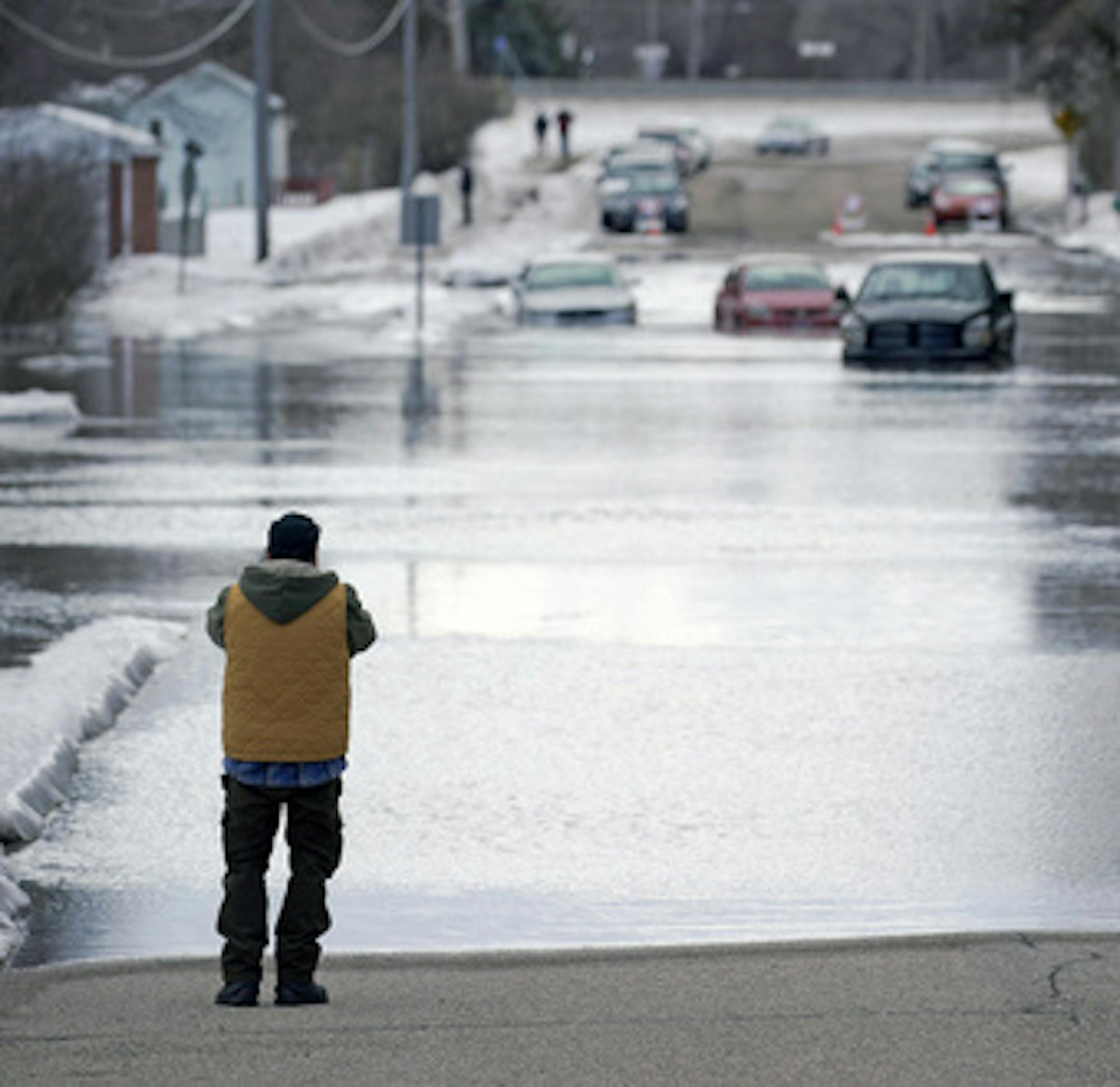 The Sand Creek in Jordan, Minn. has flooded its banks due to a large ice dam and cut off access to the Vally Green Trailer Park, Friday, March 15, 2019. This was the view of Syndicate Street with a few cars and trucks stranded in the water. (Brian Peterson/Star Tribune via AP)