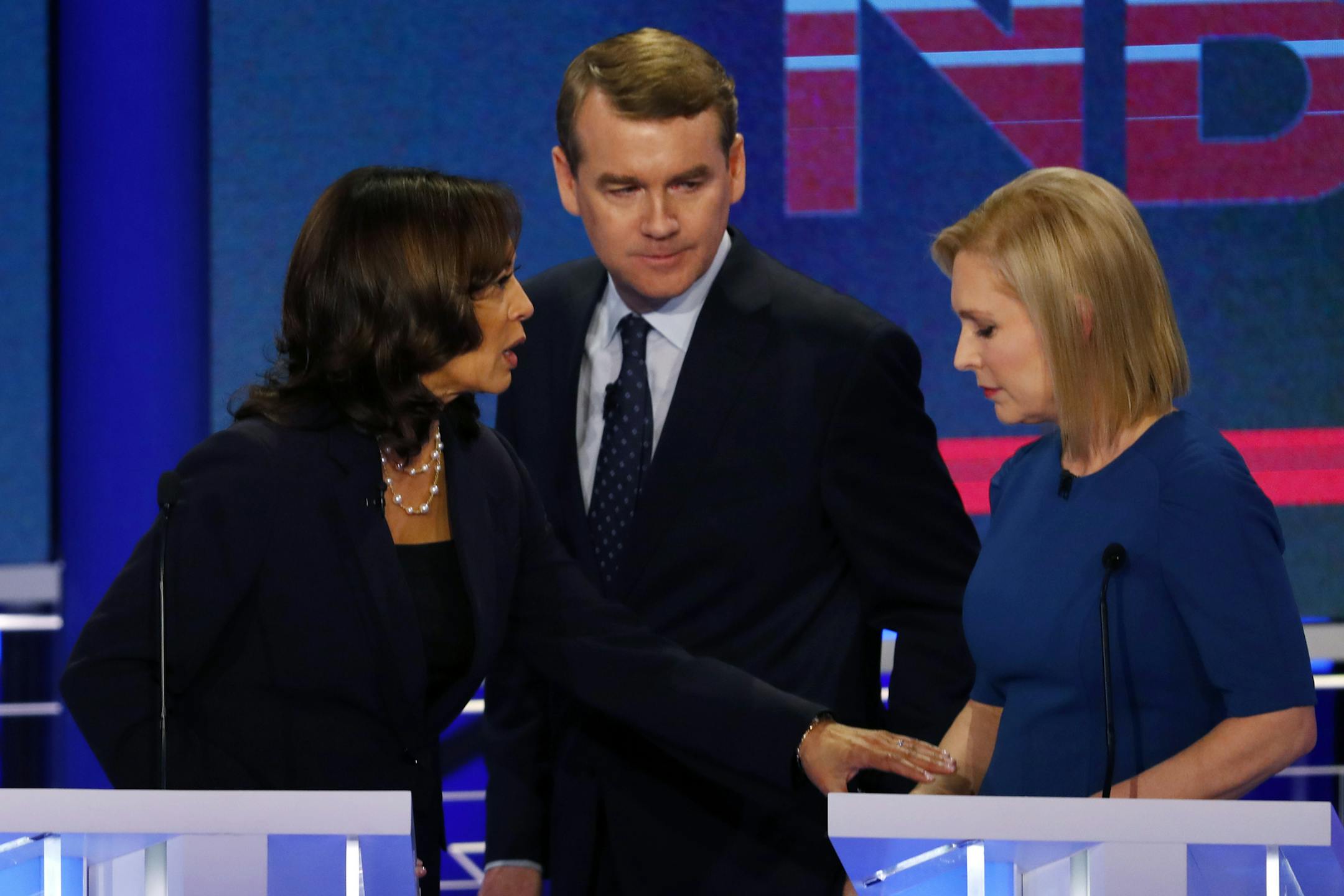 CORRECTS SPELLING OF GILLIBRAND'S FIRST NAME TO KIRSTEN, INSTEAD OF KRISTEN; CORRECTS BENNET'S TITLE TO SEN., INSTEAD OF FORMER SEN. - Democratic presidential candidate Sen. Kamala Harris, D-Calif., left, reaches out to Sen. Kirsten Gillibrand, D-N.Y., as Colorado Sen. Michael Bennet, walks between them, during a break in the Democratic primary debate hosted by NBC News at the Adrienne Arsht Center for the Performing Art, Thursday, June 27, 2019, in Miami. (AP Photo/Wilfredo Lee)