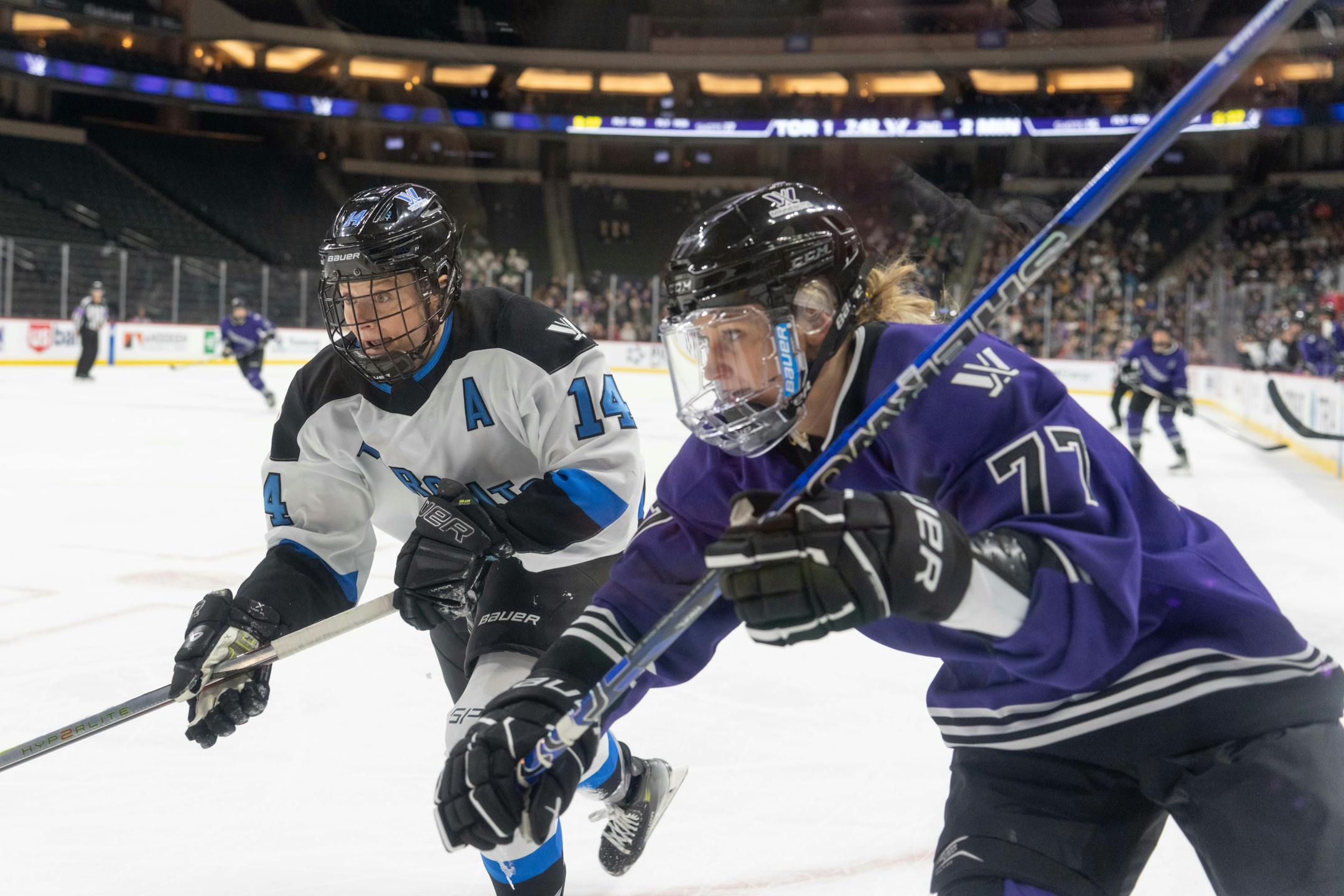 Toronto defender Renata Fast (14) and Minnesota forward Susanna Tapani (77) chase the puck into the corner in the second period between Minnesota and Toronto of the PWHL at the Xcel Energy Center in St. Paul on Wednesday, Jan. 10, 2024. Photo by Matt Blewett, Special to Star Tribune matt@mattebphoto.com