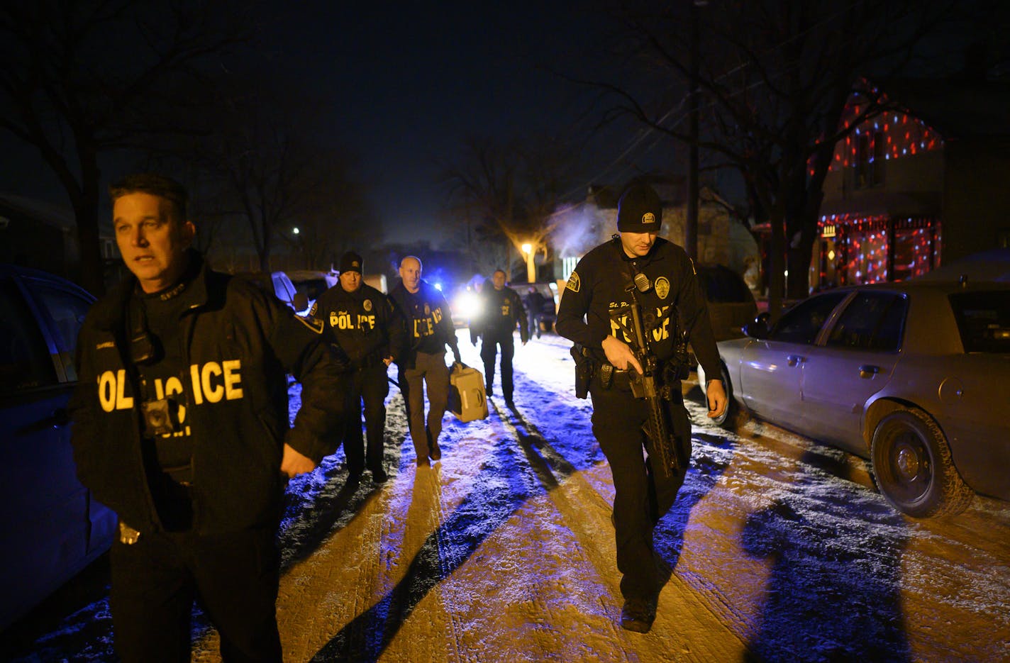 Members of the St. Paul Police Department's gang unit, including Sgt. Shawn Campbell, left, and officer Colby Bragg, right, returned to their cars after searching a home in connection with a 2019 shooting.