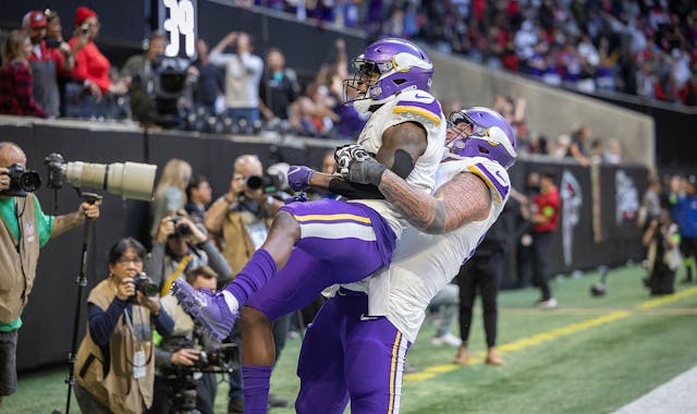 Vikings guard Dalton Risner (66) lifts Vikings wide receiver Brandon Powell (4) as they celebrate Powell's touchdown in the fourth quarter at Mercedes