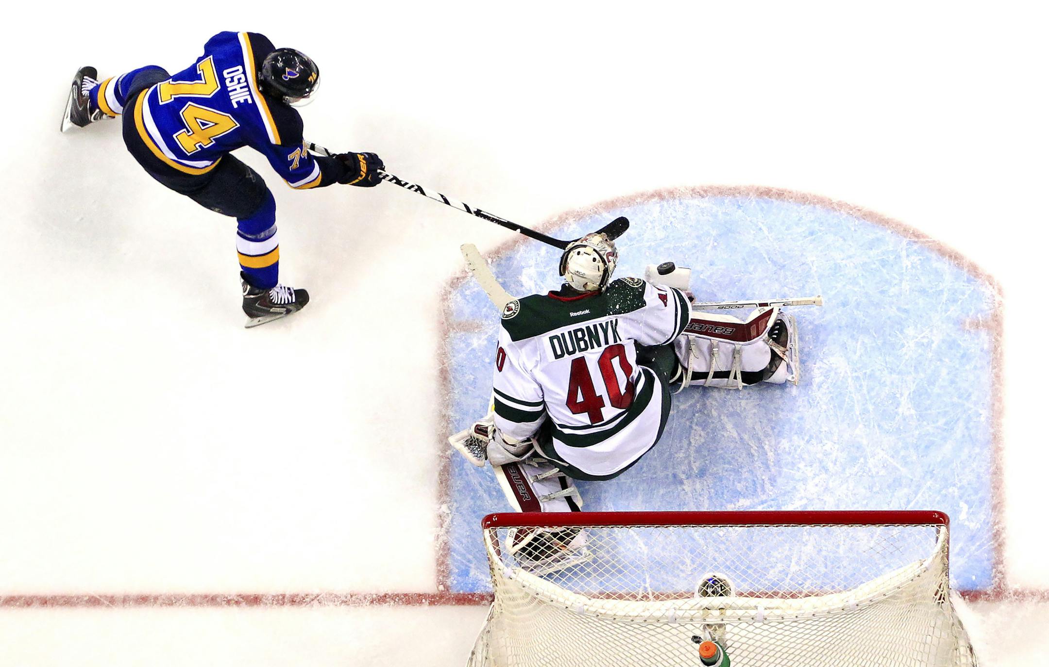 St. Louis Blues' T.J. Oshie, left, takes a shot against Minnesota Wild goalie Devan Dubnyk during the second period of an NHL hockey game Saturday, March 14, 2015, in St. Louis. Minnesota won the game 3-1. (AP Photo/Billy Hurst)