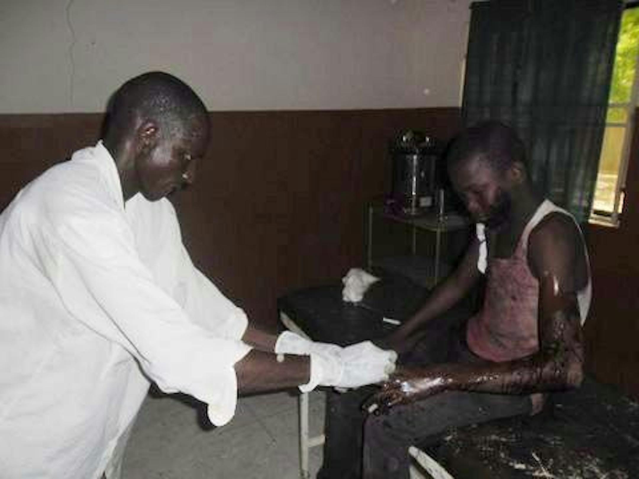 In this photo taken with a mobile phone a doctor attends to a student from Government Secondary School in Mamudo, at the Potiskum General Hospital, Nigeria, following an attack by gunmen on Saturday July 6, 2013. Islamic militants attacked a boarding school before dawn Saturday, dousing a dormitory in fuel and lighting it ablaze as students slept, survivors said. At least 30 people were killed in the deadliest attack yet on schools in Nigeria's embattled northeast.
