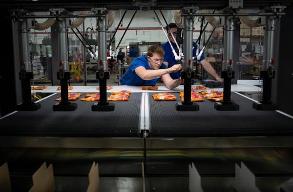 Intern and new hire Hans Sarkinen, a Hennepin Technical College graduate, on Friday adjusts a robot head on a machine that packages gummy bear candies