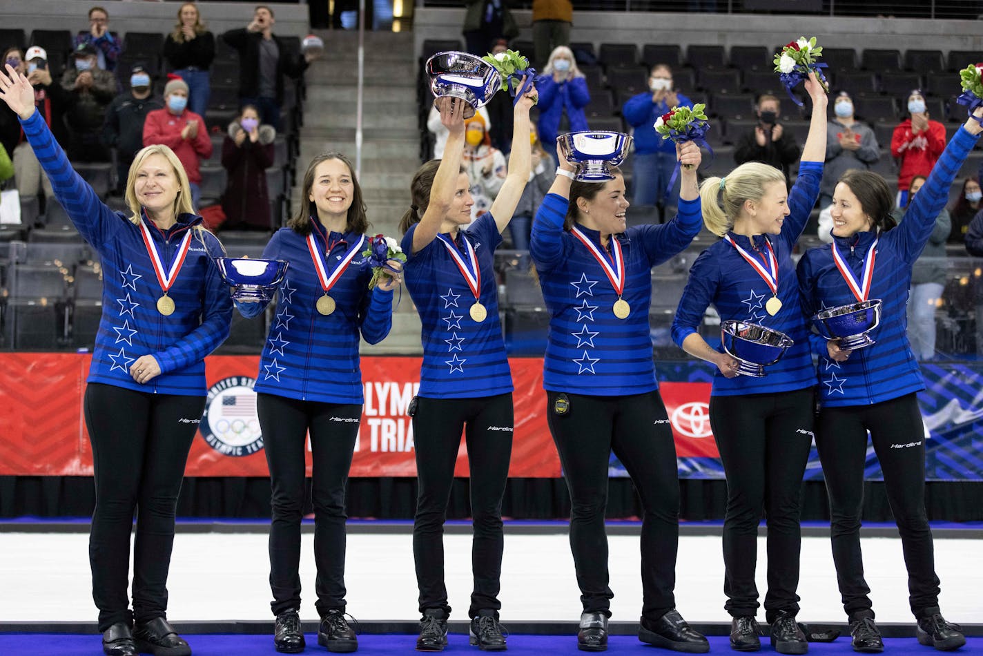 From left, Team Peterson's coach Laine Peters, alternate Aileen Geving, Tara Peterson, Becca Hamilton, Nina Roth and Tabitha Peterson wave to fans during the medal presentation following their victory over Team Christensen during the second night of finals at the U.S. Olympic Curling Team Trials at Baxter Arena in Omaha, Neb., Saturday, Nov. 20, 2021. Team Peterson won the match and will represent Team USA at the 2022 Beijing Winter Olympics. (AP Photo/)