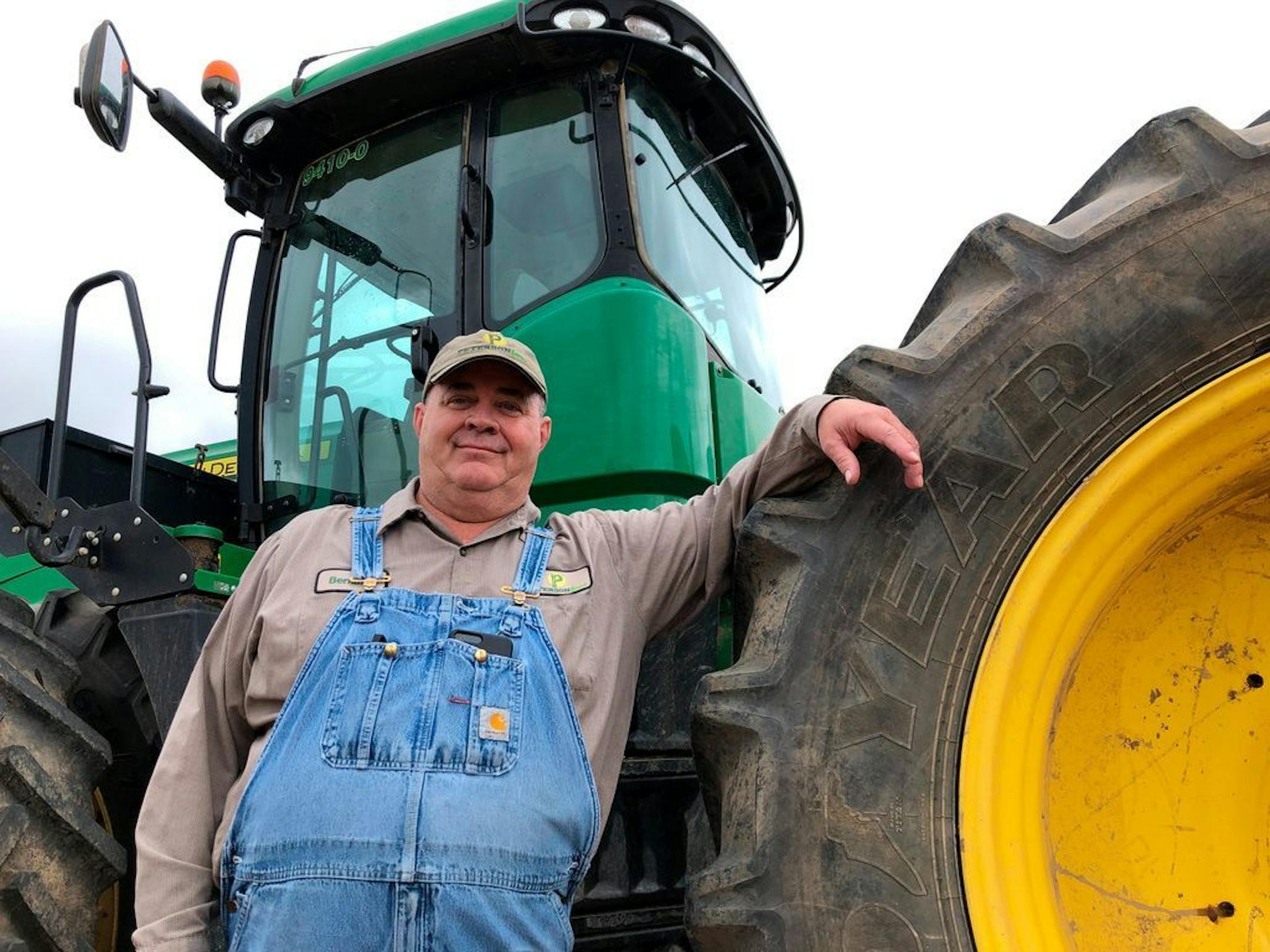 Farmer Bernard Peterson leans on a tractor at his farm in Loretto, Ky. At Peterson's farm, eight members of the family partnership collected a total $863,560 for crops they grow on over 15,000 acres in seven counties, including wheat and corn used at the nearby Maker's Mark bourbon distillery. Peterson said that it didn't make up for all their losses at a time when it was already hard to be profitable. The $1.65 per bushel aid payments for soybeans fell well short of losses he estimated at $2 to