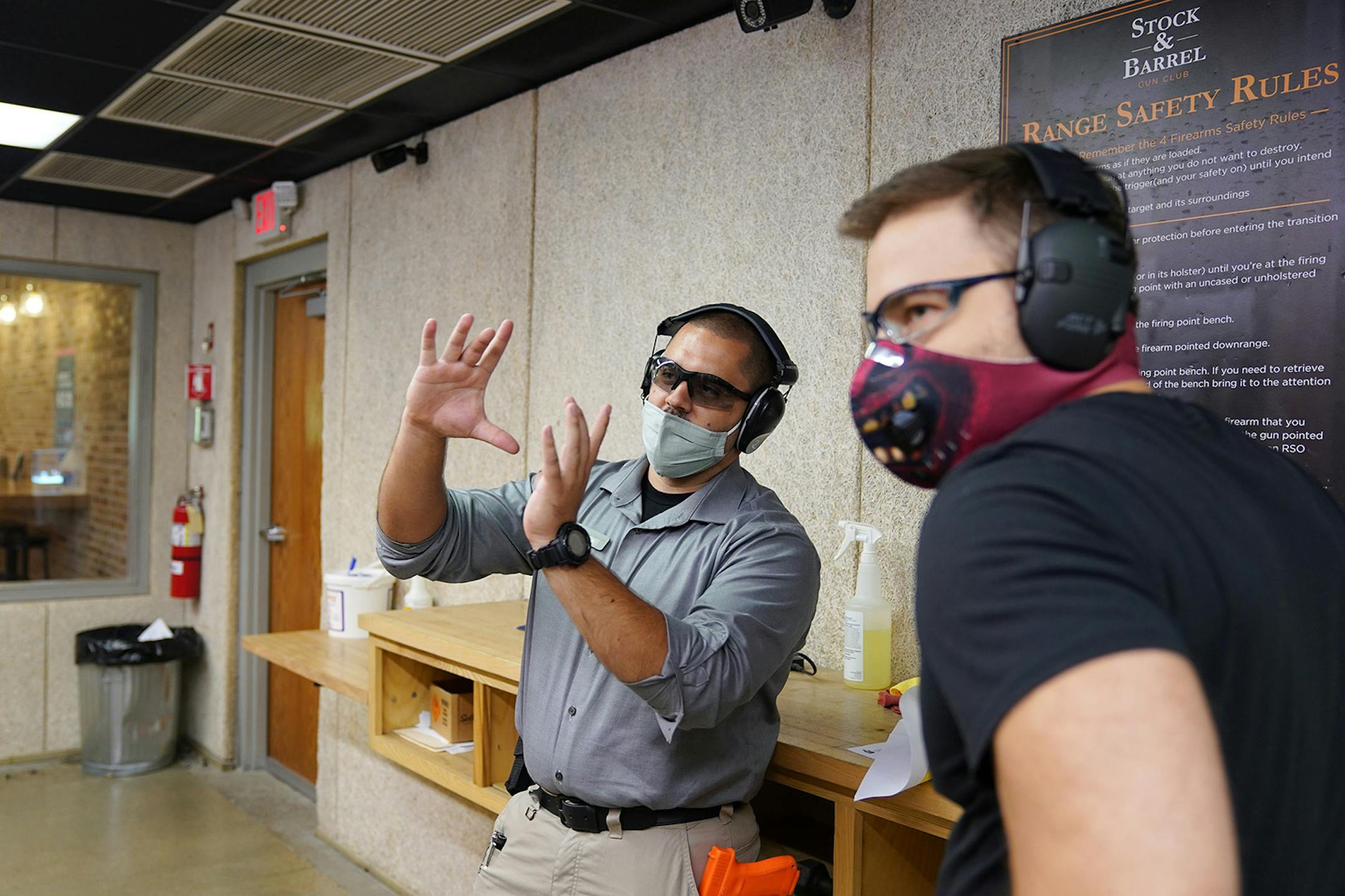 Range safety officer Carter Perez, center, talked with Stephen Schmida of Minneapolis about his spread as he shot two new guns.