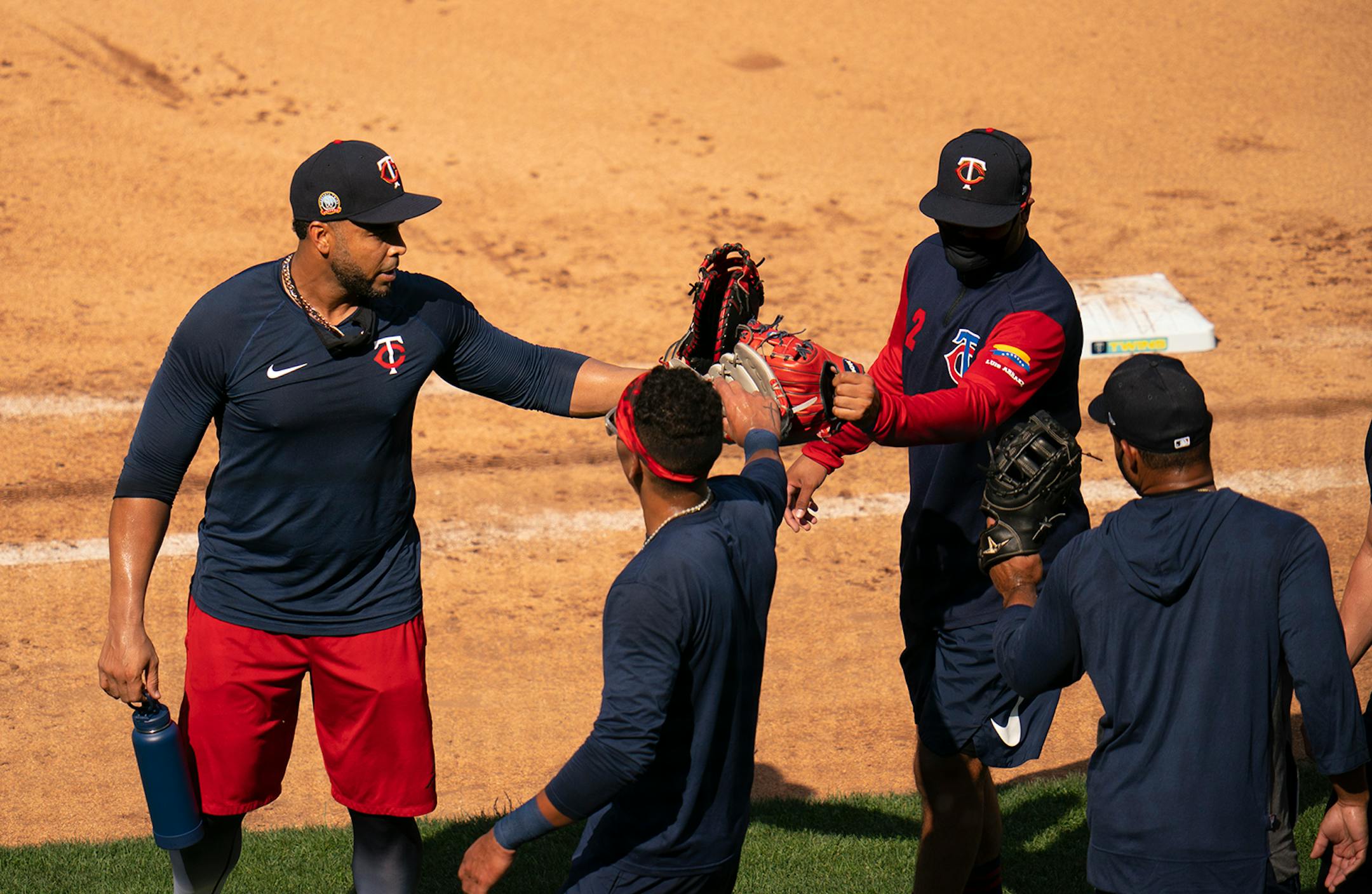 Twins players Nelson Cruz, Ehire Adrianza, and Luis Arraez, from left, touched gloves after infield practice Sunday evening.