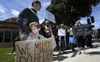 Kyle Fox, 4, and his father Brady Fox hold a sign at a vigil held to support the victims of Chabad of Poway synagogue shooting on the last day of Pass