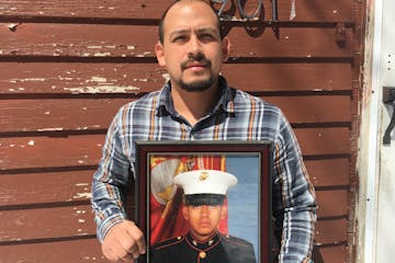 In this April 13, 2019, photo provided by the ACLU of Minnesota, Mark Esqueda poses for a portrait with a photo of him as a U.S. Marine, in Heron Lake