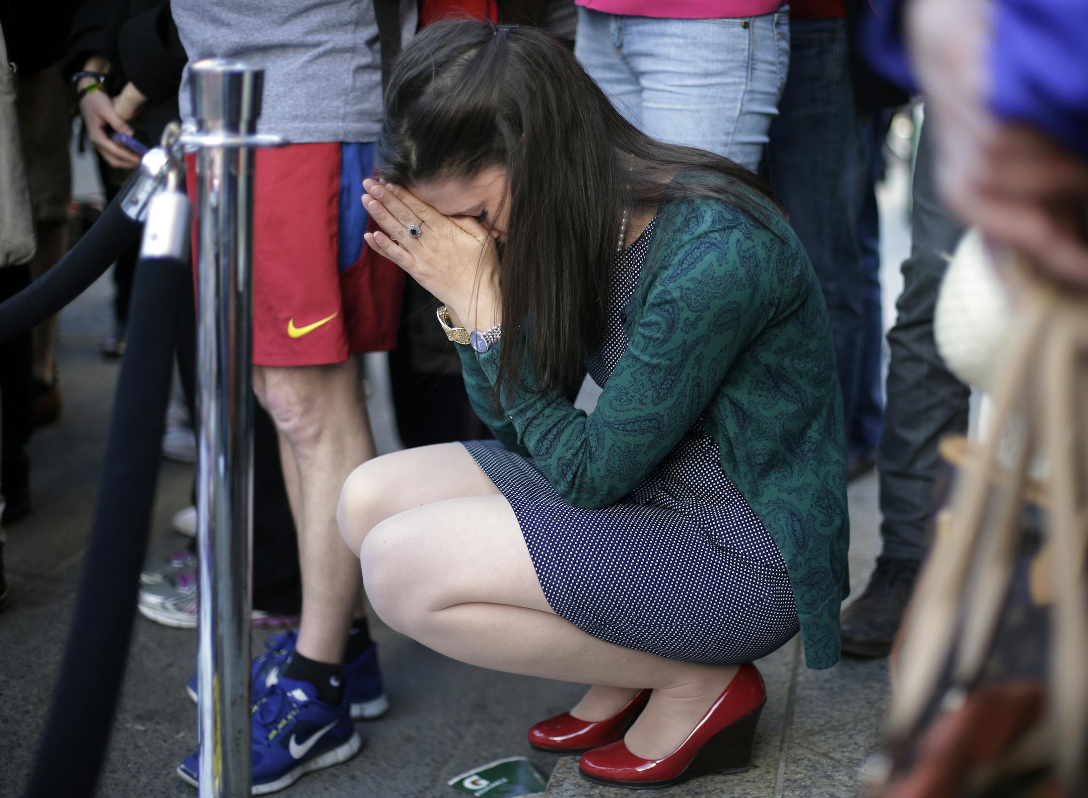 Jennifer Krewalk attends a makeshift memorial on Boylston Street near the finish line of Monday's Boston Marathon explosions, which killed at least three and injured more than 140, Wednesday, April 17, 2013, in Boston. (AP Photo/Matt Rourke)
