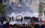 FILE - In this Nov. 30 1999, file photo, Seattle police use tear gas to push back World Trade Organization protesters in downtown Seattle. Saturday, N